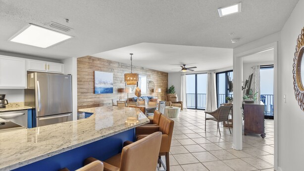 A modern kitchen with a central island, stainless steel appliances, and a dining area with bar stools.
