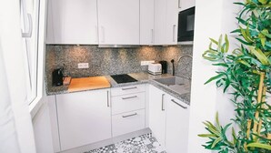 A compact kitchen with white cabinets, a granite countertop, a toaster, and a sink.