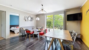 A modern living room with a sofa, chairs, a dining table, and a TV. - Charming house on the heights of St Jacques with sea view (Sarzeau)