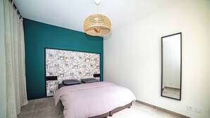 A bedroom with a bed, a large wall-mounted mirror, and a ceiling light fixture.