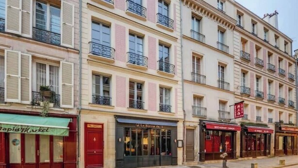 A row of multi-story buildings with commercial establishments on the ground floor, including a bakery and a restaurant.