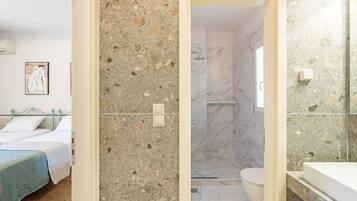 Une chambre avec un lit, une salle de bain avec une douche et des toilettes.