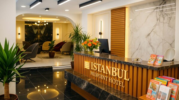 A reception desk at the Istanbul Midpoint Hotel with a marble floor, potted plants, and a view into the lobby area. - Istanbul Midpoint Hotel (Istanbul)