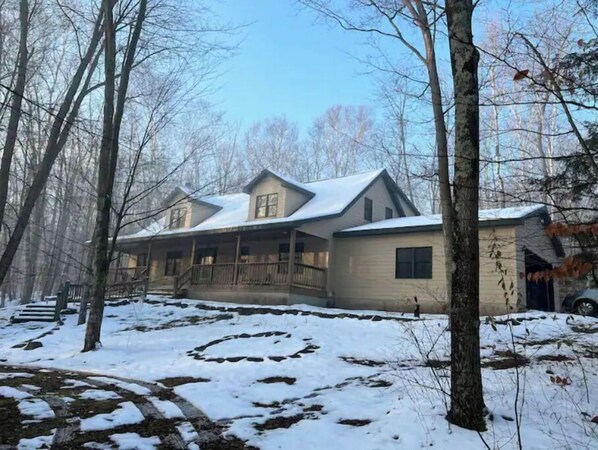 Una casa de dos pisos con un porche y un patio cubierto de nieve.