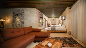 A cozy living room with a sectional sofa, a wooden coffee table, and a bed with a floral bedspread.
