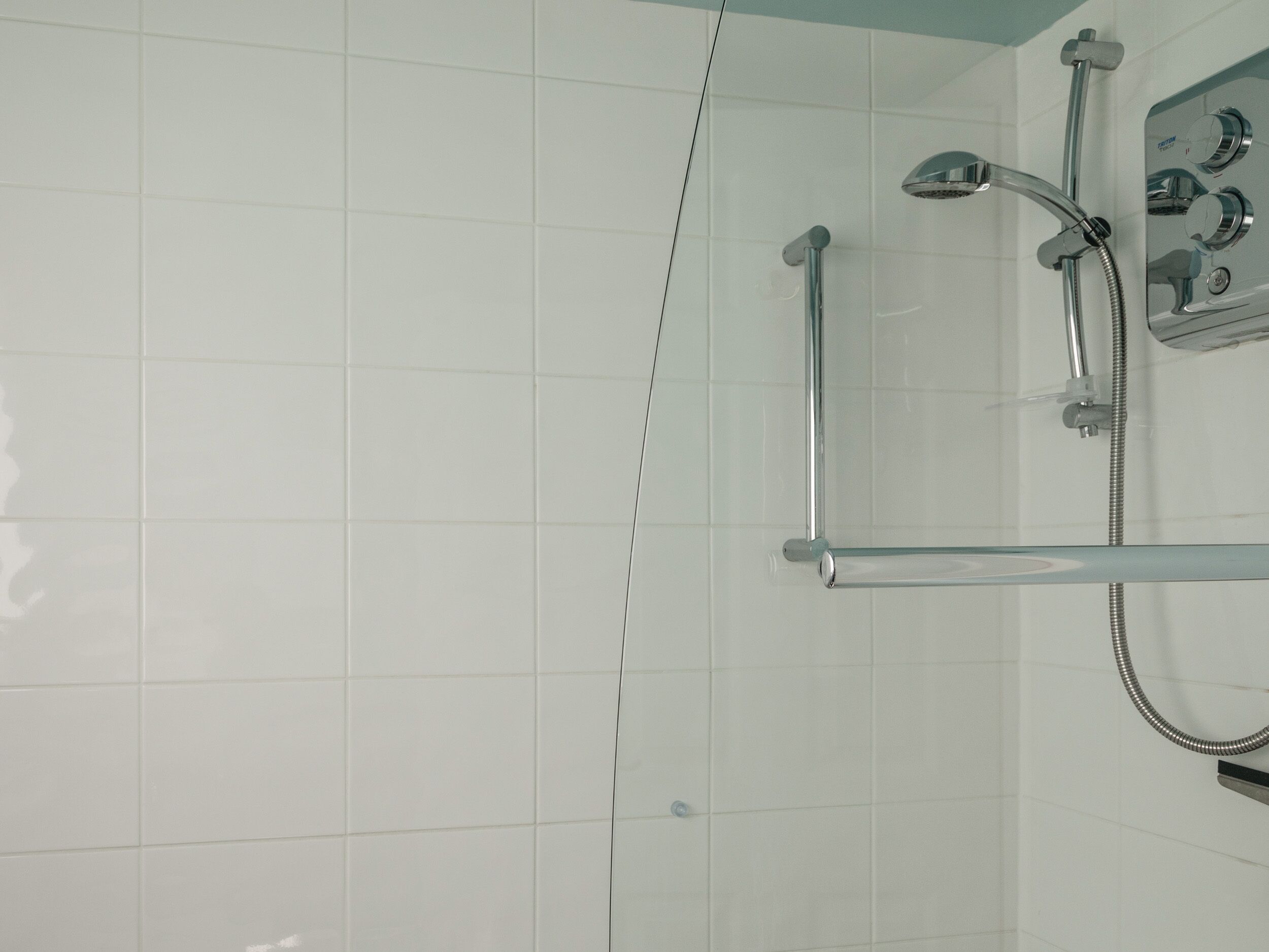 A modern shower with chrome fixtures, a glass door, and a control panel on the wall.