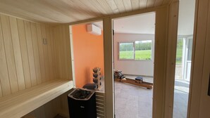 Uma sala de sauna com paredes de madeira, um banco e um aquecedor de sauna.