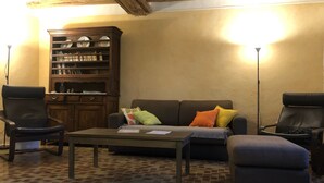 Uma sala de estar aconchegante com um armário de madeira, um sofá, duas poltronas e uma mesa de centro.