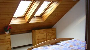 A bedroom with a sloped ceiling, skylights, a wooden bed, a dresser, and a radiator. - Apartment WIENERWALDquiet, conveniently located, villa-green area, pet-friendly (Wien)
