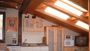A compact kitchen with wooden cabinets, a coffee maker, a microwave, and a television. - Apartment WIENERWALDquiet, conveniently located, villa-green area, pet-friendly (Wien)