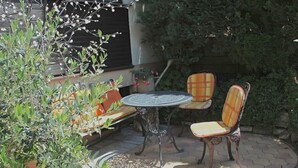 An outdoor patio with a round table and two chairs, surrounded by potted plants and a bench. - Apartment WIENERWALDquiet, conveniently located, villa-green area, pet-friendly (Wien)