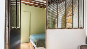 Um quarto com cama, porta e janela com persianas.