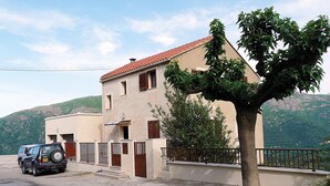 A two-story building with a red-tiled roof, a tree in front, and a parked car on the street. - LOFT CASA NEPITA TALLANO 72 m2 CLIM VUE GRANDIOSE furnished tourism 3 stars (Sainte-Lucie-de-Tallano)