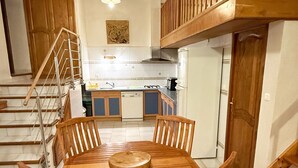 A dining area with a wooden table and chairs, a kitchen in the background, and a staircase leading to an upper level. - LOFT CASA NEPITA TALLANO 72 m2 CLIM VUE GRANDIOSE furnished tourism 3 stars (Sainte-Lucie-de-Tallano)