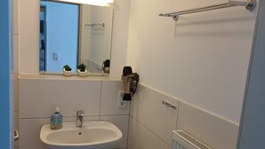 Ein kleines, modernes Badezimmer mit Waschbecken, Spiegel und Handtuchhalter.