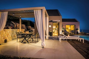 Eine moderne Terrassengruppe mit Essbereich, Pool und überdachter Lounge-Ecke.
