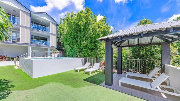 Um edifício moderno com piscina no terraço, área de estar externa e um pátio coberto.