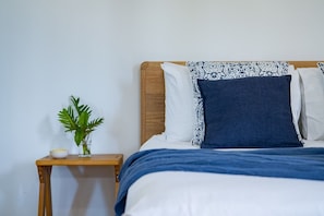 Ein Bett mit einem Holz-Kopfteil, blau-weiß gemusterten Kissen und einer blauen Decke.
