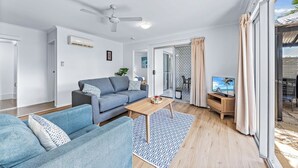 Uma sala de estar moderna com um sofá, uma mesa de centro e uma televisão.