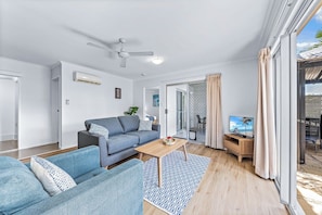 A modern living room with a sofa, a coffee table, and a TV. - Casa D' Amore' (Airlie Beach)