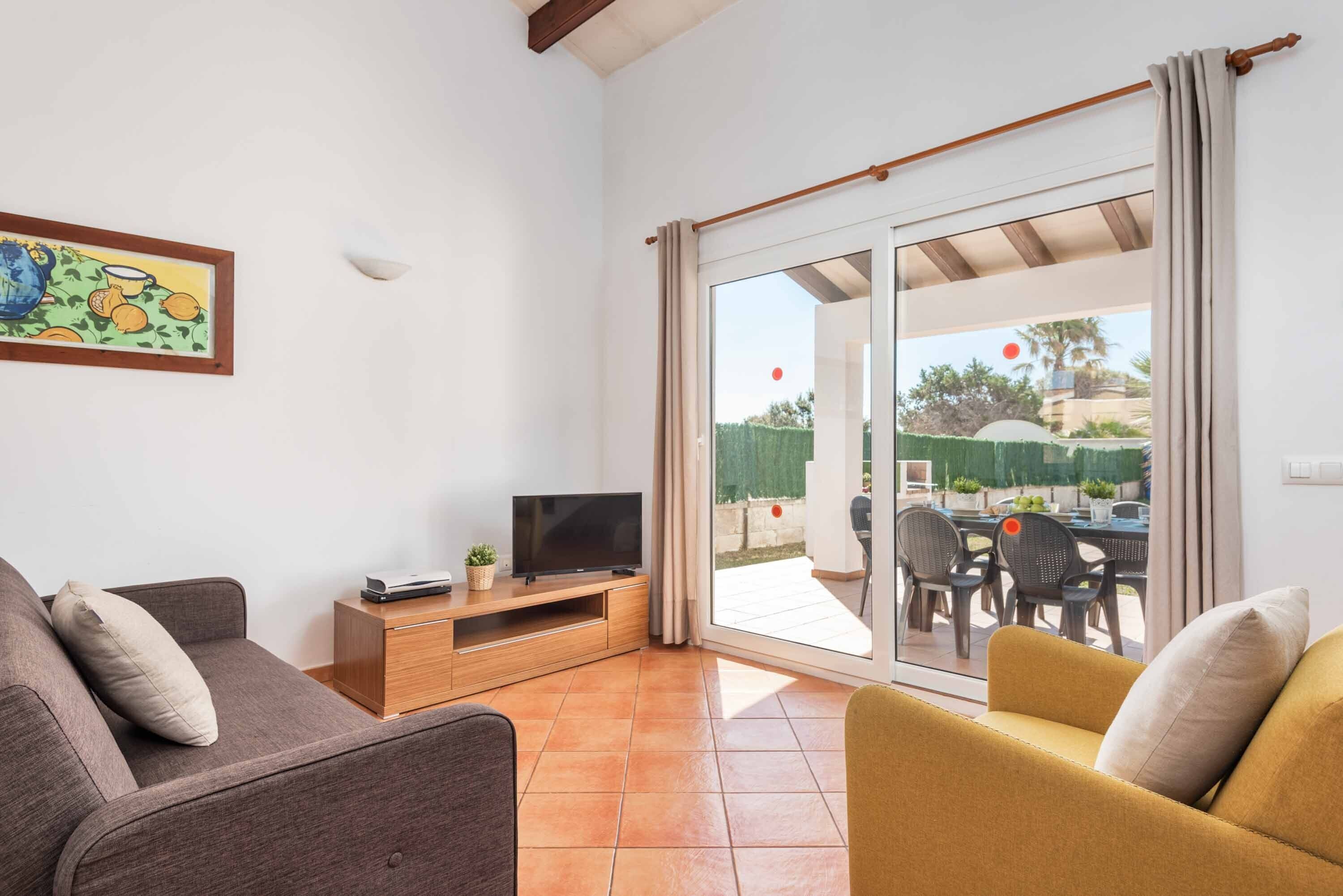 Una sala de estar con sofá, televisor y un comedor con sillas y mesa.