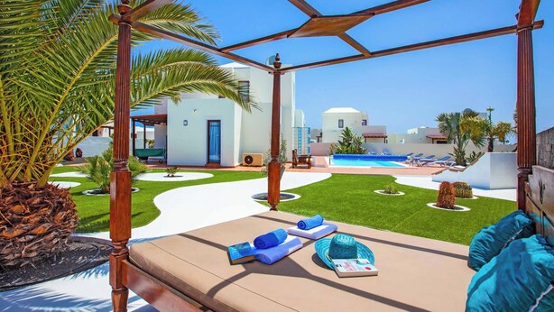 Un espace aménagé au bord de la piscine, avec une pergola en bois, des chaises longues et une piscine.