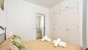 Una habitación de hotel con una cama, un armario y un baño visible a través de una puerta abierta.