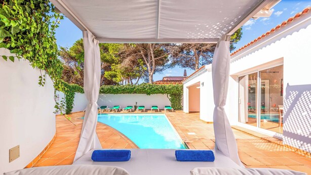 Zona de piscina con un área de estar cubierta y vistas a la piscina.