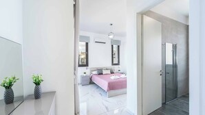 A modern bedroom with a bed, bedside tables, a mirror, and a door leading to a bathroom.