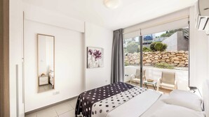 A bedroom with a bed, a large window, a chair, and a small table. - Villa Latchi View - Three Bedroom Villa, Sleeps 6 (Neo Chorio)