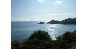 A coastal landscape with a clear view of the sea, a small island, and hills in the distance. - Lodge l'Immortelle (Zonza)