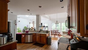 Una cocina amplia con armarios de madera, una isla central y una zona de comedor con sillas.