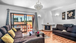 Ein Wohnzimmer mit Sofa, Couchtisch, Kamin und Blick durch eine Glastür.