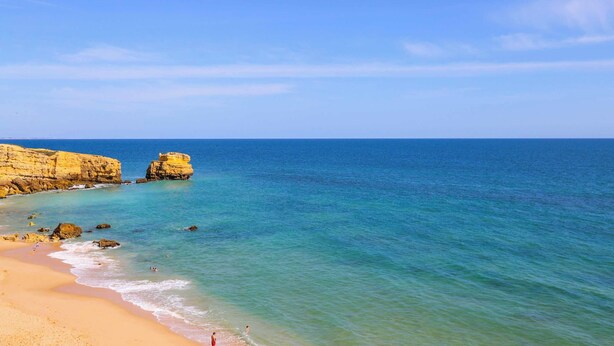 Una spiaggia con acque cristalline, una riva sabbiosa e scogliere rocciose.
