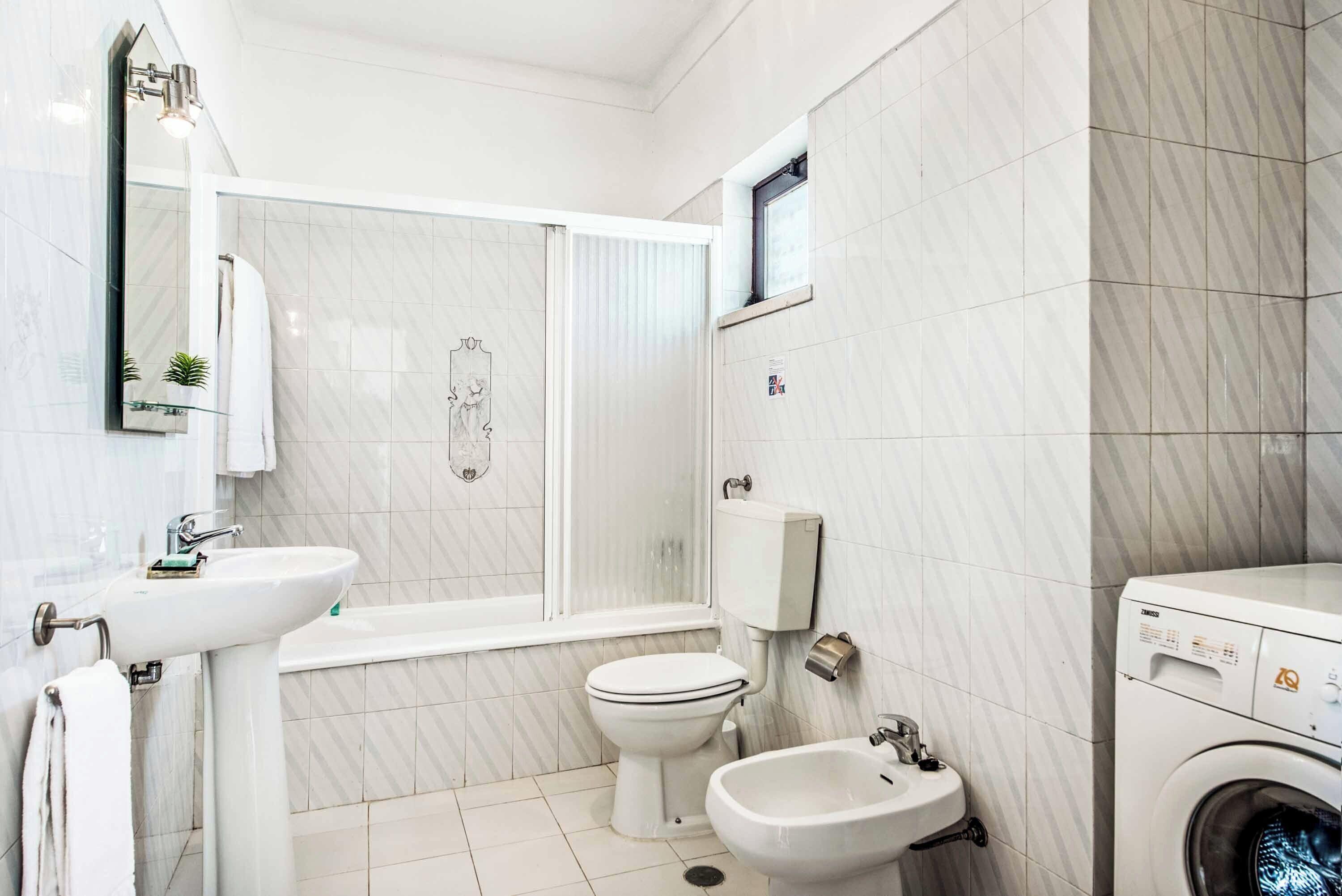 A modern bathroom with a toilet, bidet, sink, and washing machine.