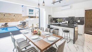 A modern kitchen with white cabinets, a marble countertop, and a built-in oven. - Vie Bleu 1 - Four Bedroom Villa, Sleeps 8 (Πρωταράς)