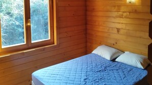A wooden cabin room with a bed, a window, and a wall-mounted light fixture. - La Tinutella 2, la tinutella (Olmeto)