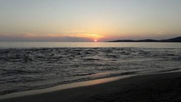 Une plage avec un coucher de soleil sur l’océan.