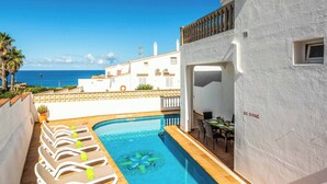 A pool area with lounge chairs, a pool with a star-shaped design, and a view of the sea.