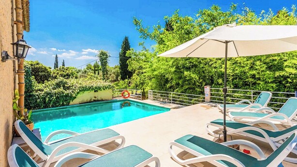 Ein Schwimmbecken mit Liegestühlen und Sonnenschirm.