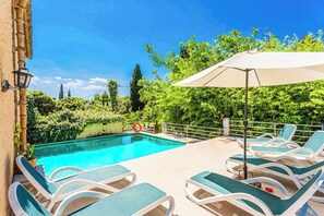 Ein Schwimmbecken mit Liegestühlen und Sonnenschirm.