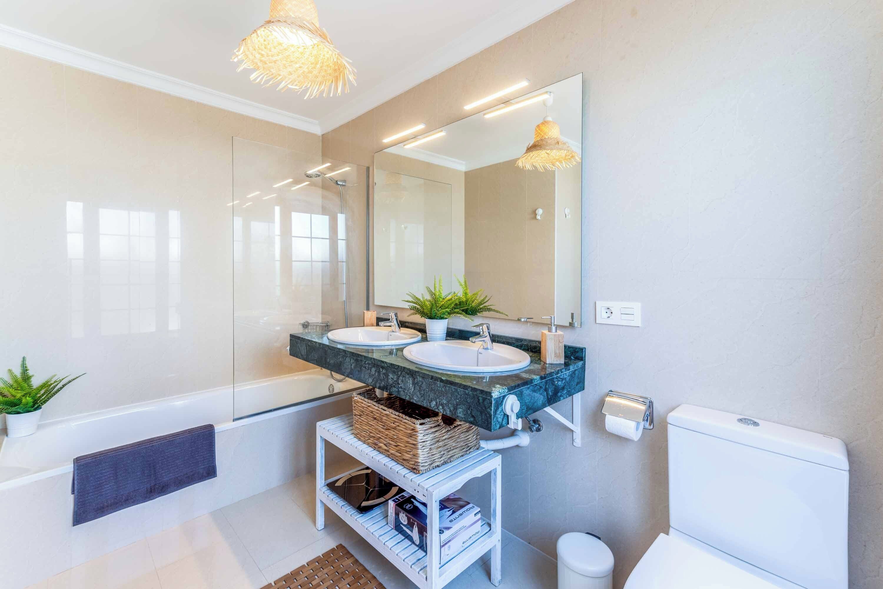 Een moderne badkamer met twee wastafels, een grote spiegel en een bad.