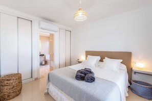 A neatly arranged bedroom with a bed, bedside tables, and a hanging light fixture.