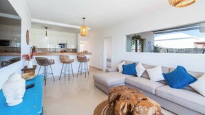 A modern living room with a sofa, a coffee table, and a dining area with chairs. - Villa Samui - Four Bedroom Villa, Sleeps 8 (Playa Blanca)