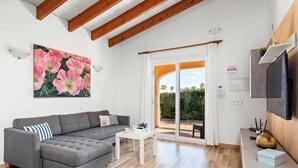 Una sala de estar moderna con un sofá seccional gris, una mesa de centro blanca y un ventanal con vistas a zonas verdes.