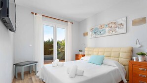 Un dormitorio con cama, un banco, una mesita de noche y un cuadro en la pared.