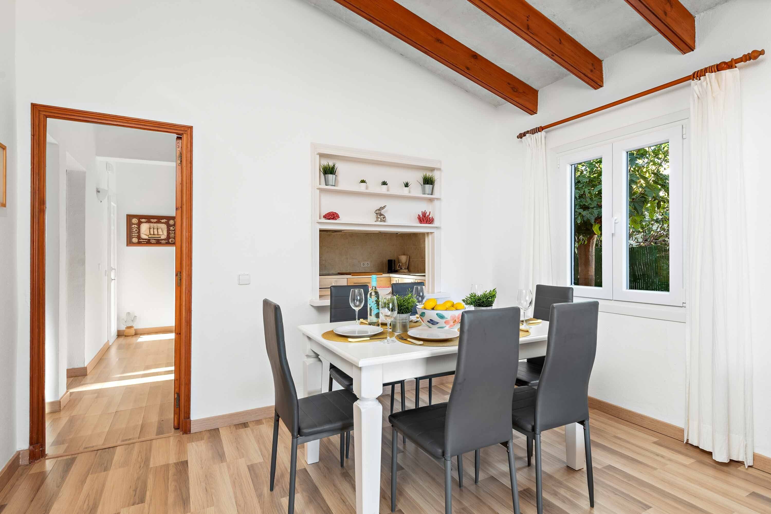 A dining area with a white table, black chairs, and a white cabinet with plants.