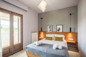 Une chambre d’hôtel avec un lit, un radiateur, une porte donnant sur une vue agréable et deux cadres photos accrochés au mur.