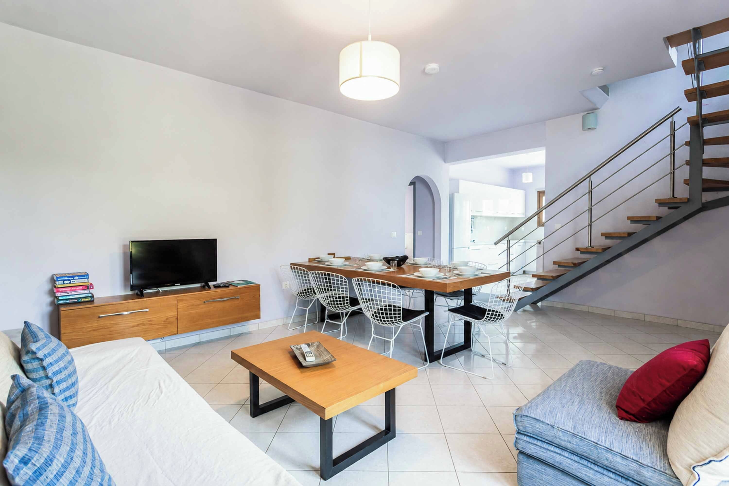 Un salon moderne comprenant un téléviseur, un canapé, une table basse et un coin repas.