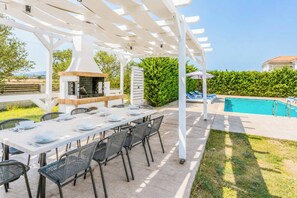Eine Außenpatio mit Pool, Grillplatz und überdachter Essgegend.